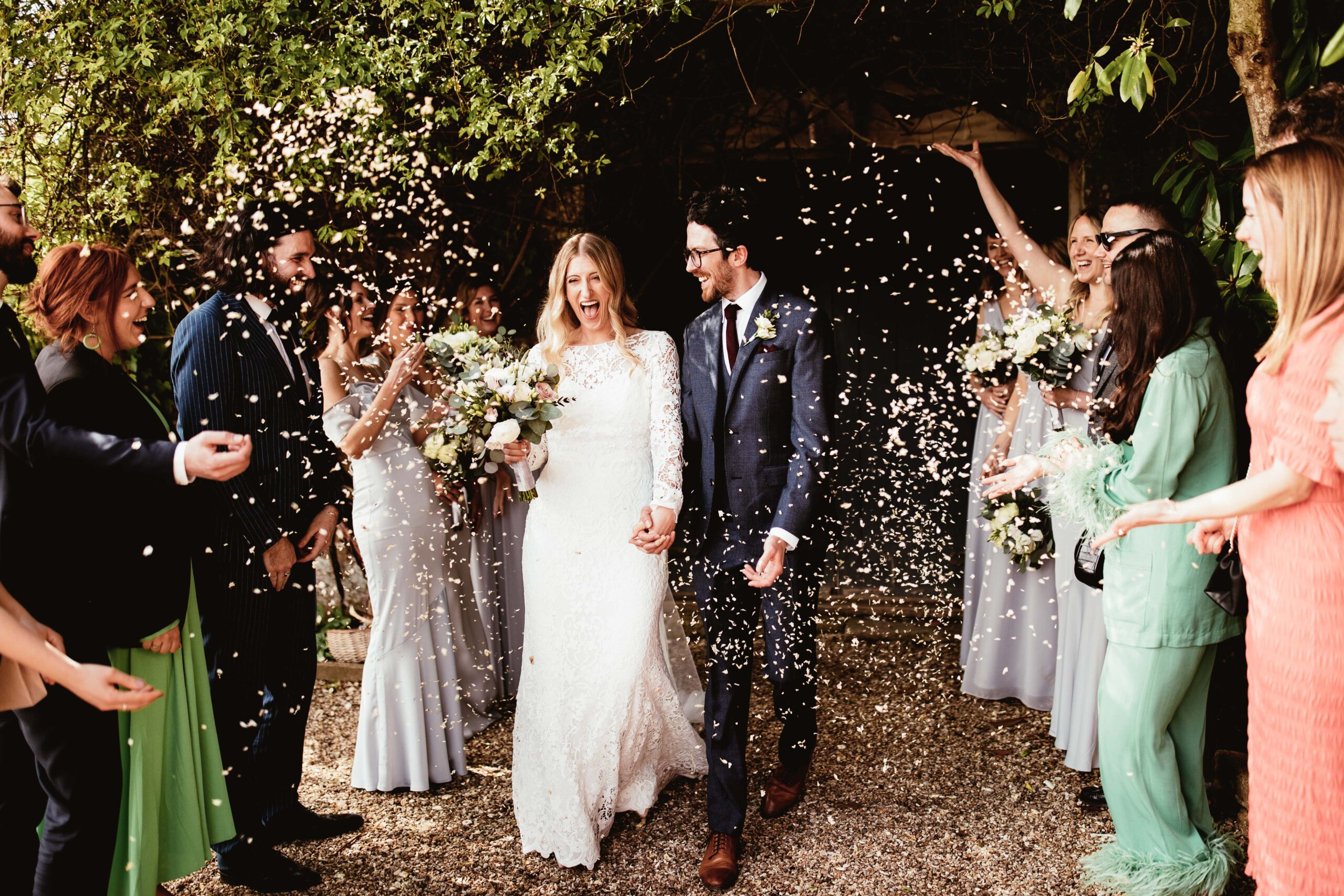 Couple walking outside during confetti moment with guests at their wedding venue in the south west called Brympton House