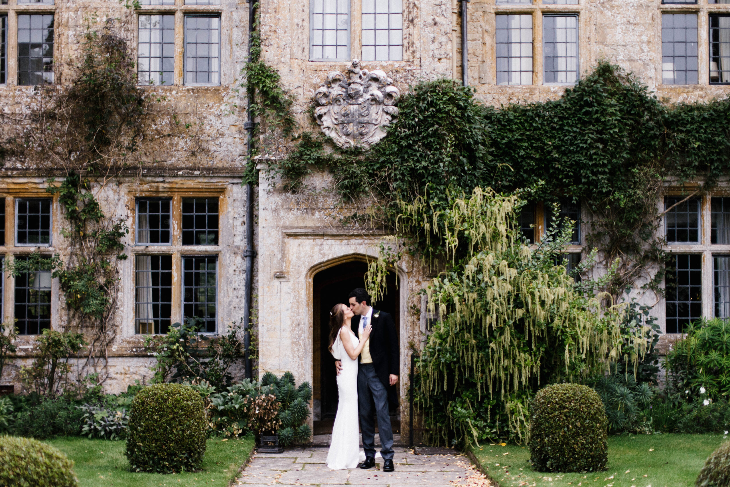 Bride and groom kissing standing outside of a south west wedding venue called Mapperton House