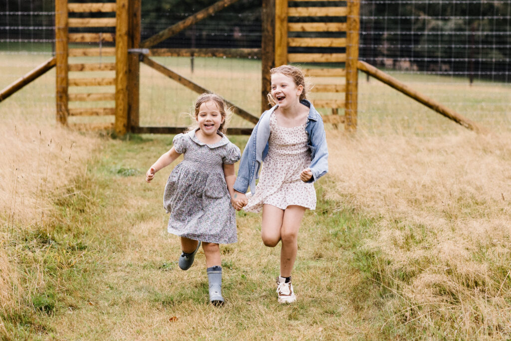 Outdoor family photo in Bristol of children running hand in hand through a field 