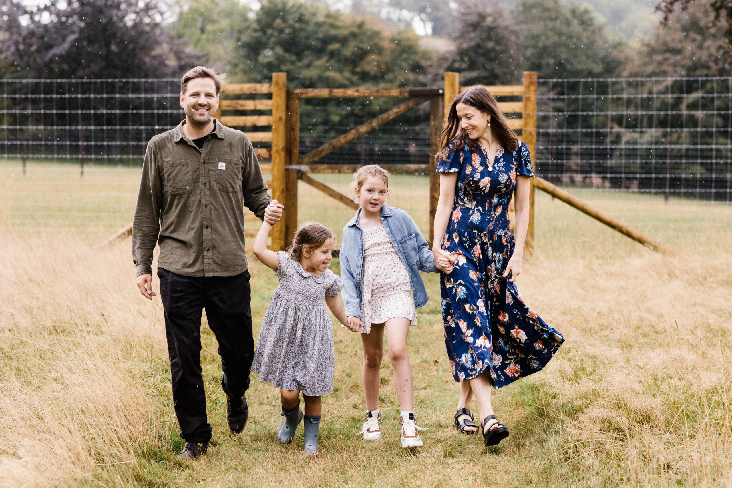 Outdoor family photo in Bristol of family all holding hands walking through field 
