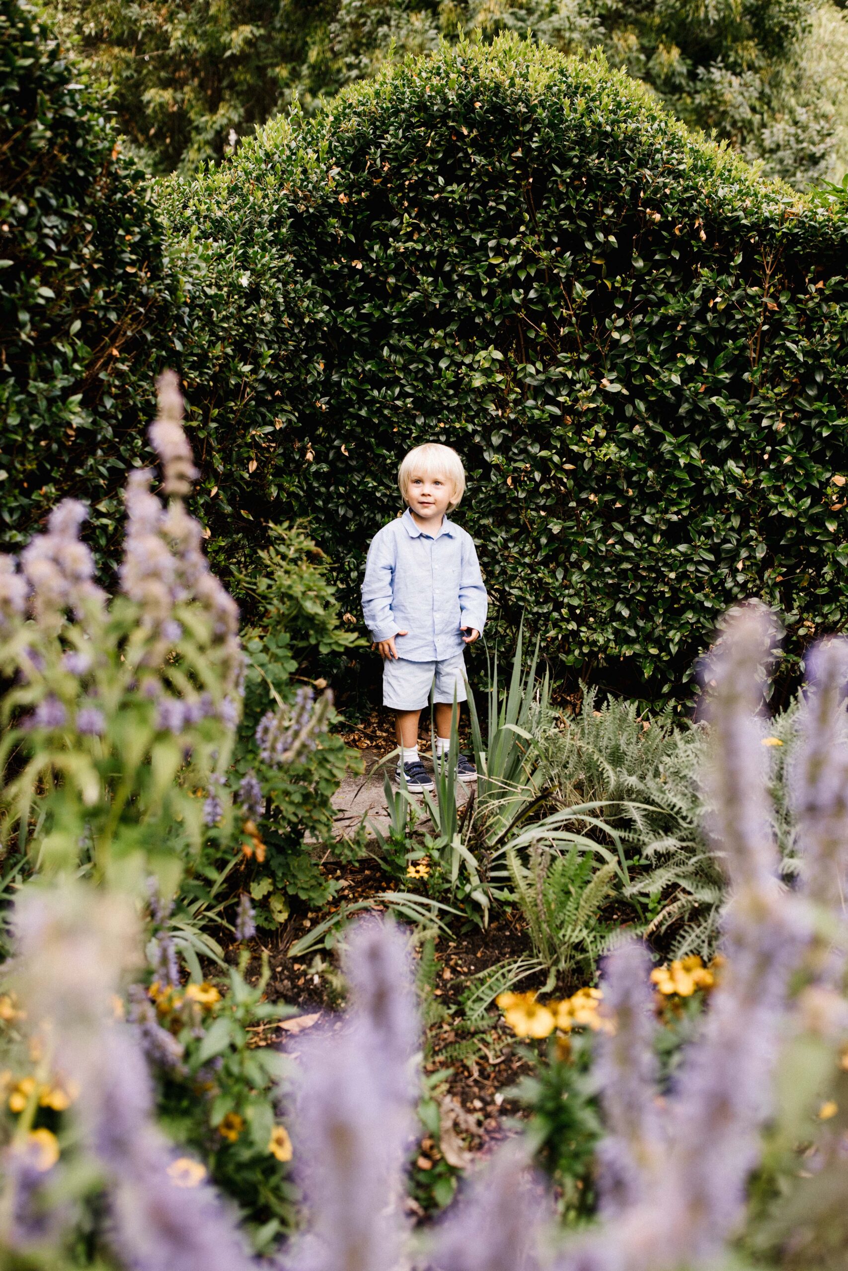 Outdoor family photo in Bristol of little boy standing smiling surrounded by greenery 