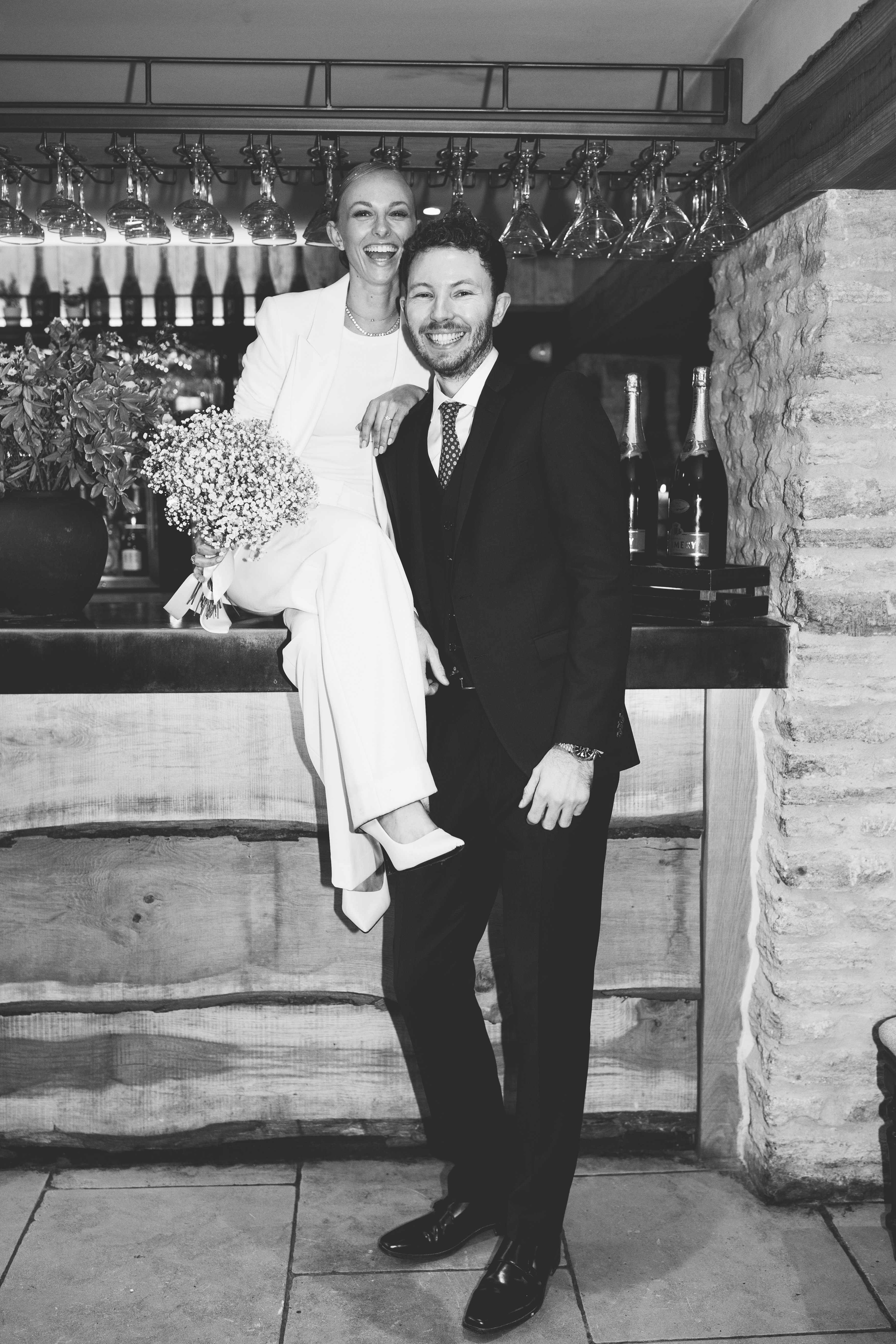 Black and white couple portrait sat at the bar at their barn wedding venue called Wild Thyme and Honey