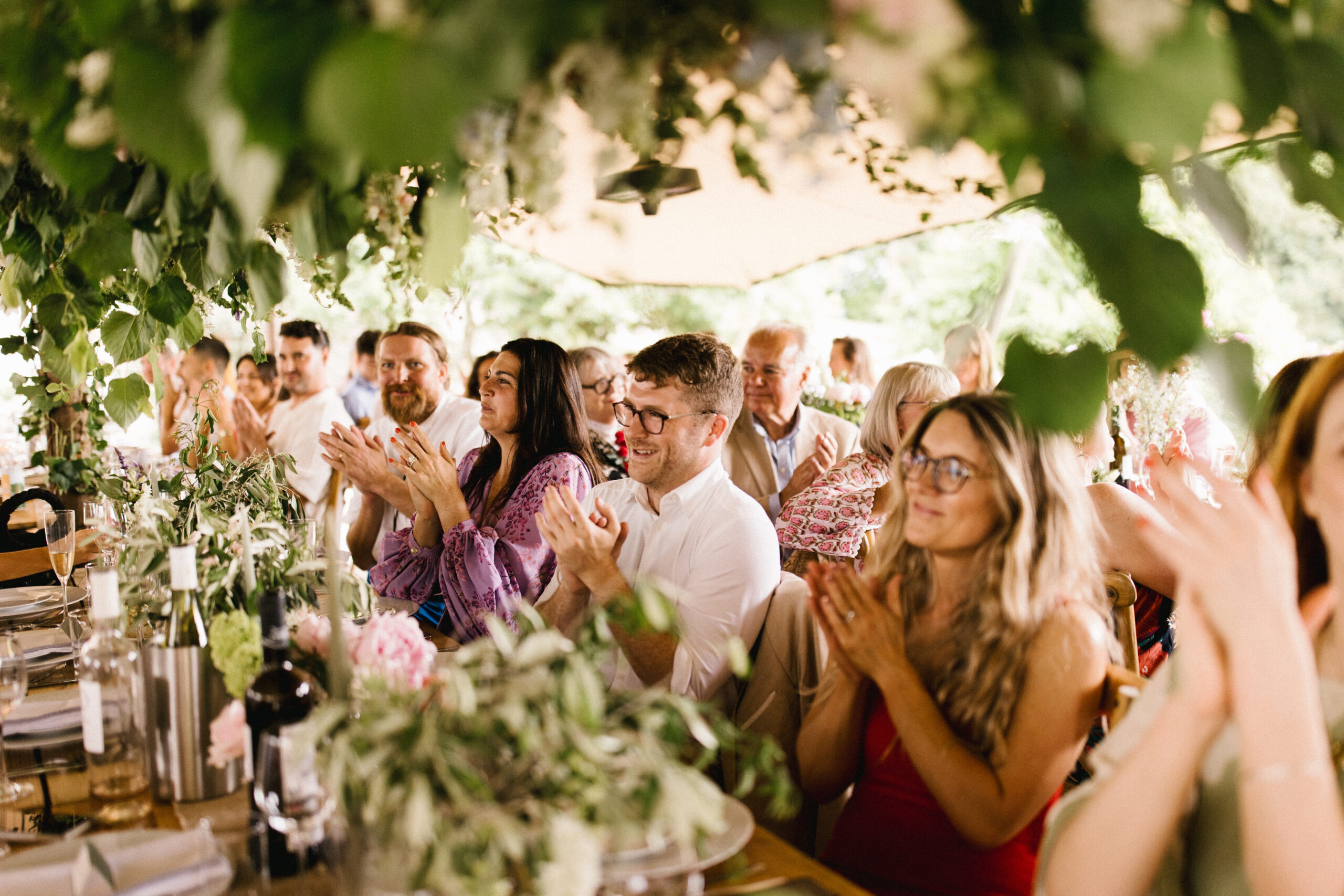 Guests smiling and clapping during speeches at their South west wedding venue at Pythouse Kitchen Garden